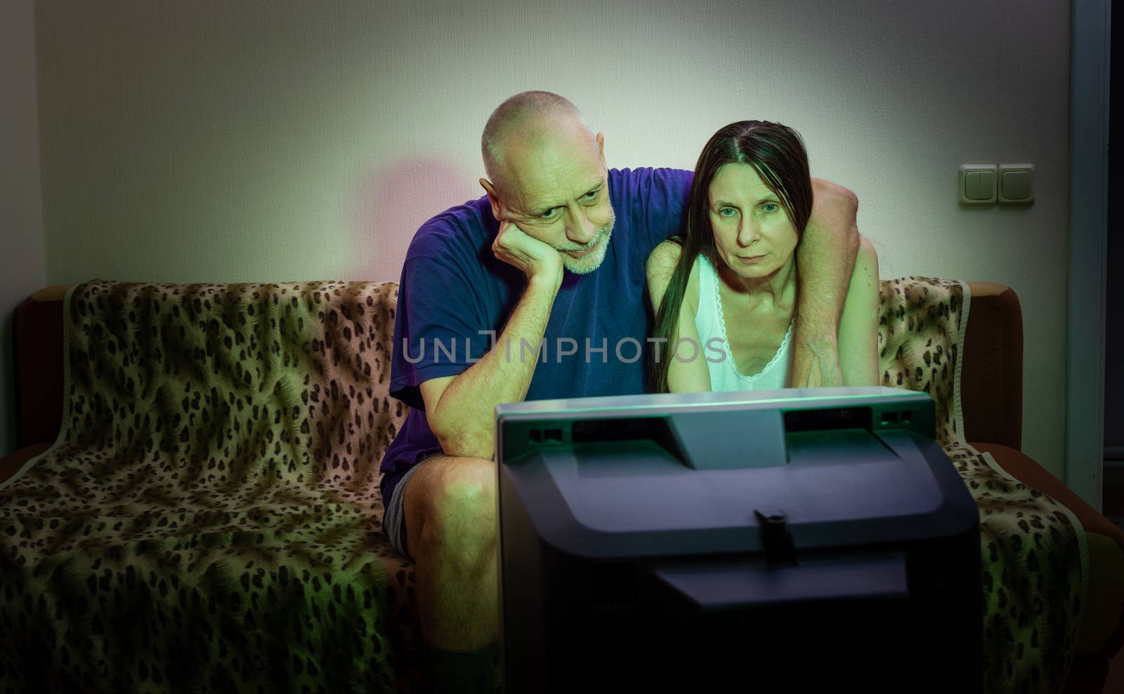 A couple of adult lovers, sitting on a couch watch movie on tele by MaxalTamor