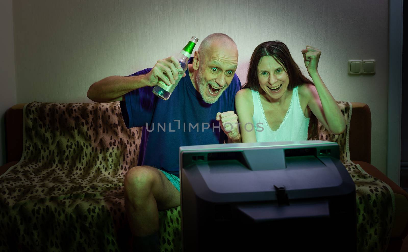 Adult man and woman watching sports on television by MaxalTamor