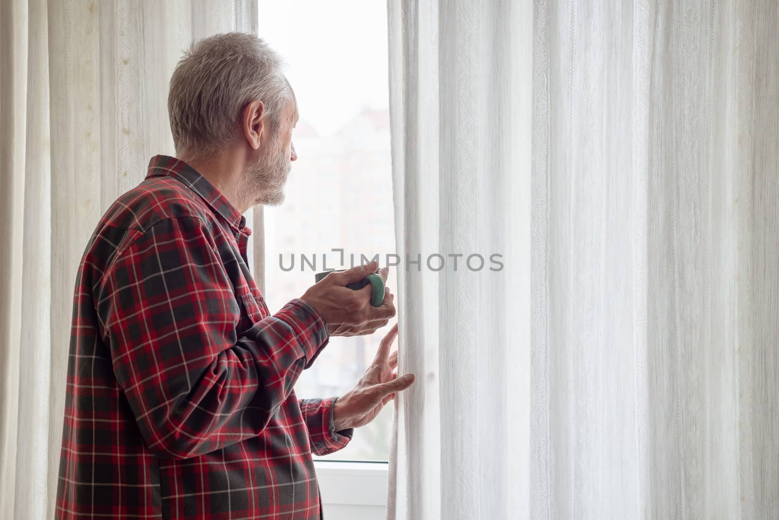 Mature man drinking his coffee and looking out of the window by MaxalTamor