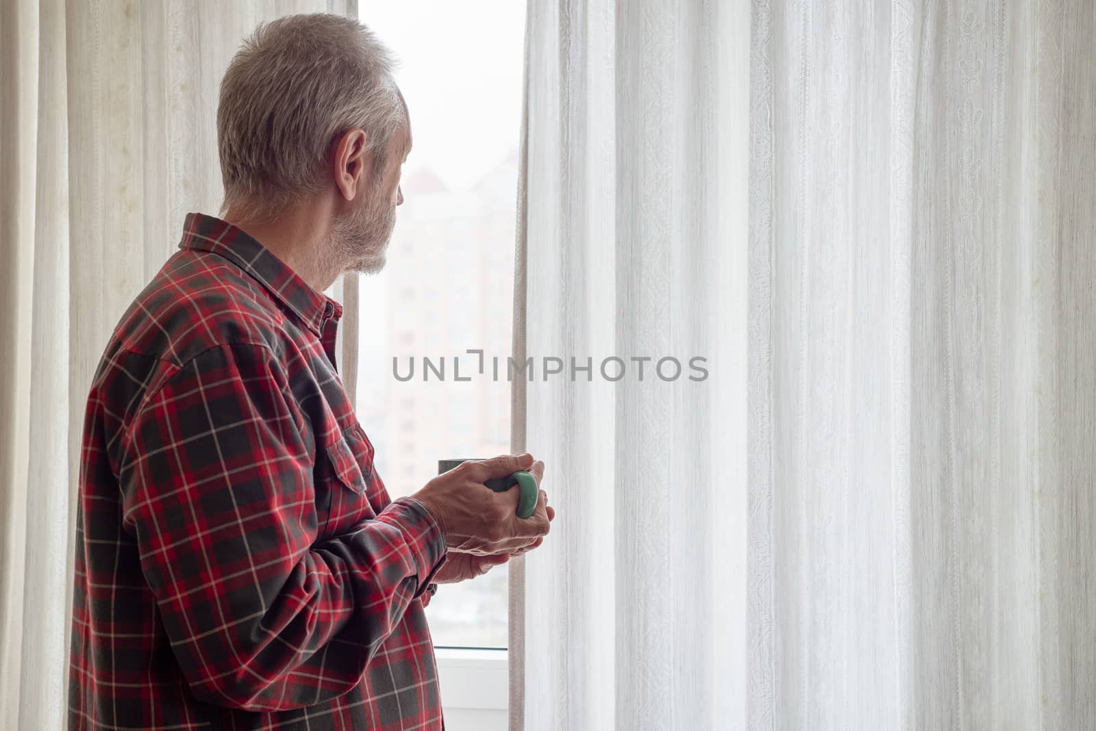 Mature man drinking his coffee and looking out of the window by MaxalTamor