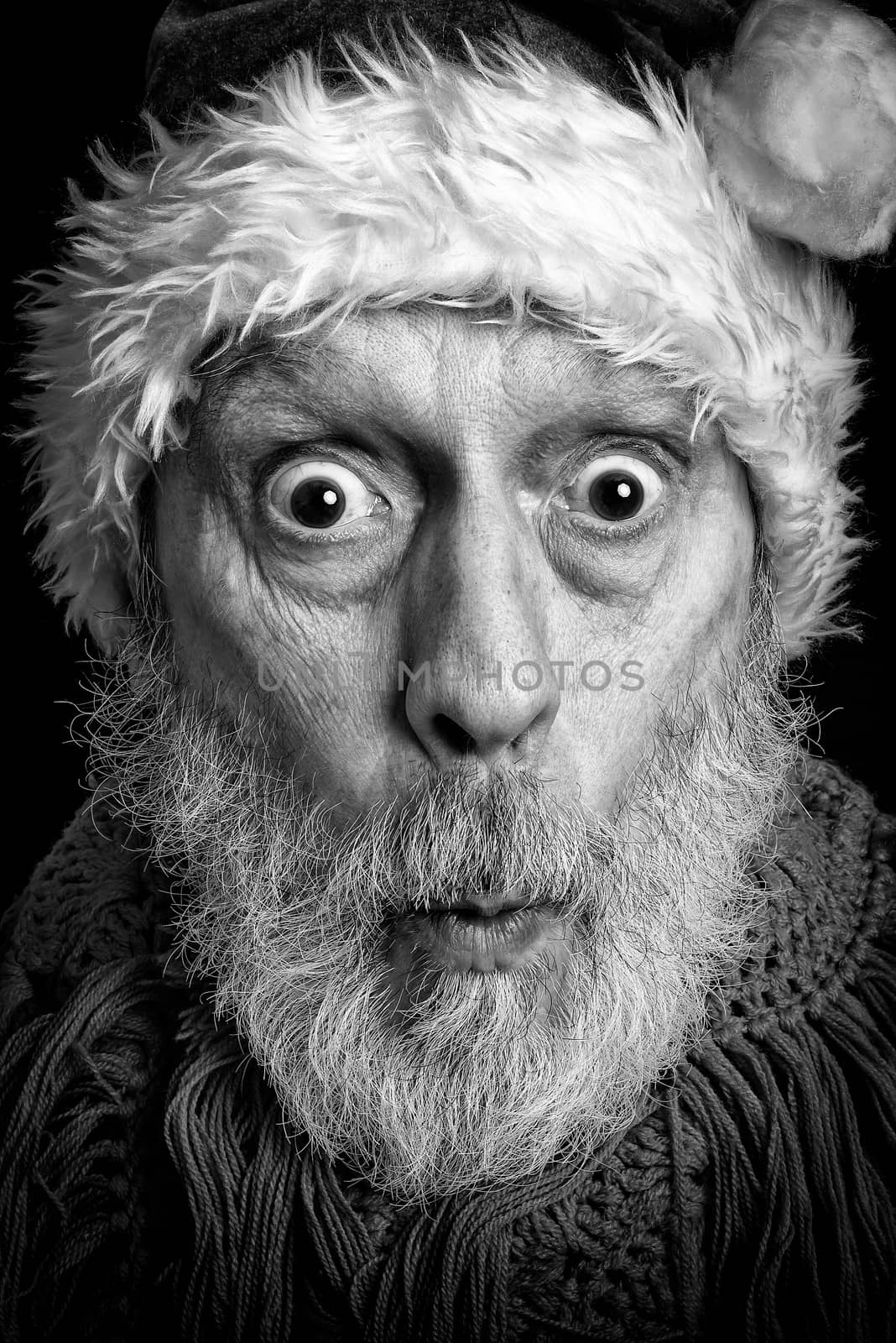 Black and white portrait of an adult man with white beard disguised in Santa Claus for the Christmas Holiday