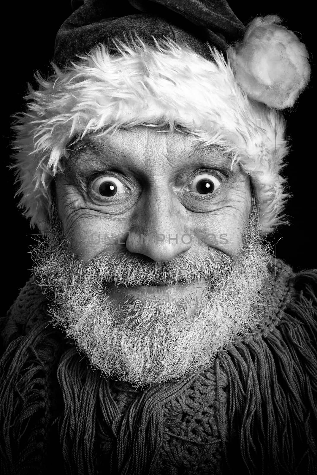 Black and white portrait of an adult man with white beard disguised in Santa Claus for the Christmas Holiday