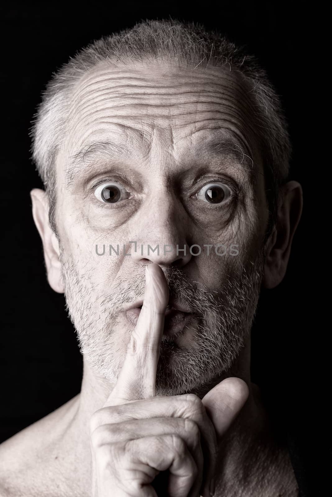 Portrait of an attractive adult man putting the finger in front of the mouth and saying "Hush!"