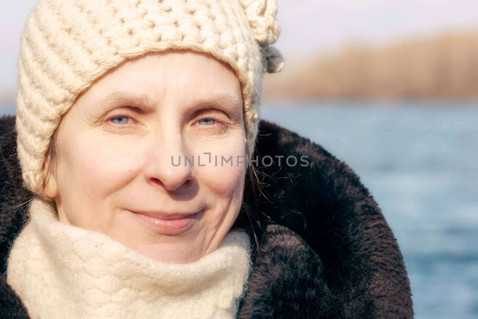 Portrait of an adult woman wearing a fur and a woolen cap in winter