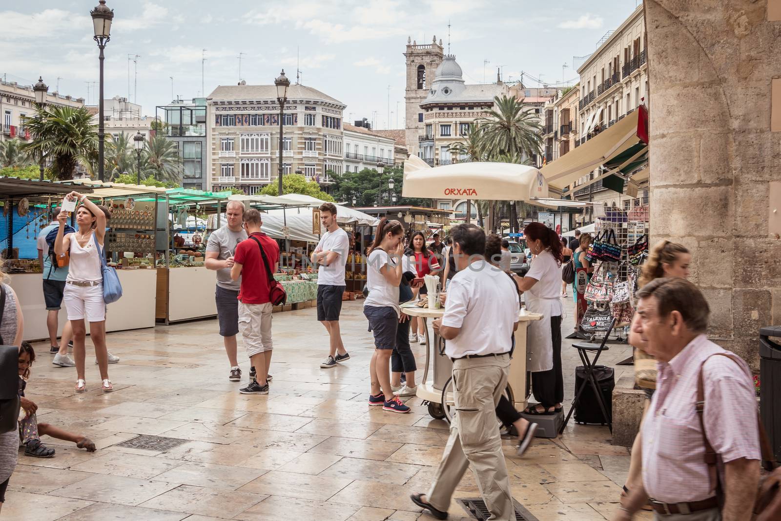 Valencia, Spain - June 16, 2017: Street atmosphere on the square of Valencia Cathedral where people are walking on a street market day in spring