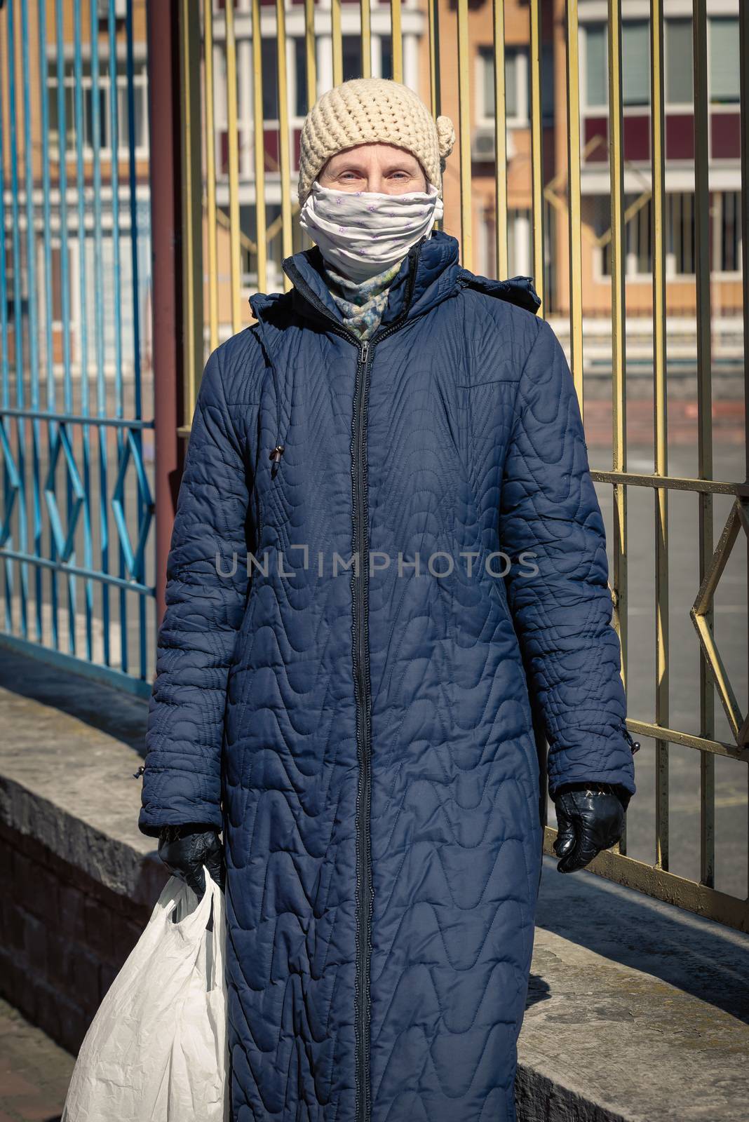A poor elderly woman wears a homemade mask to protect herself from viruses such as coronavirus, also known as covid-19, or SARS and MERS. She's in an urban environment