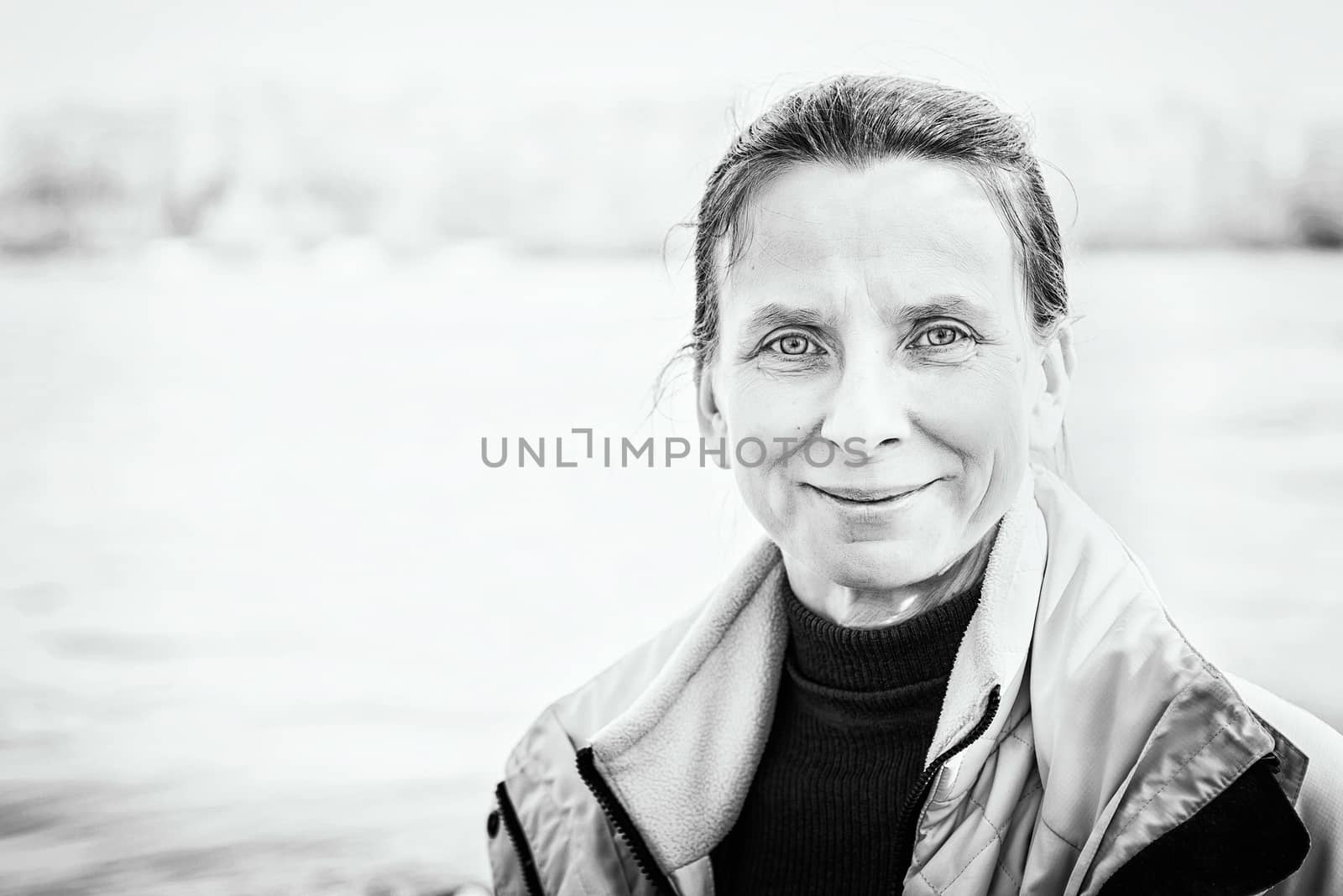 A warm portrait of a nice smiling senior woman close to the river
