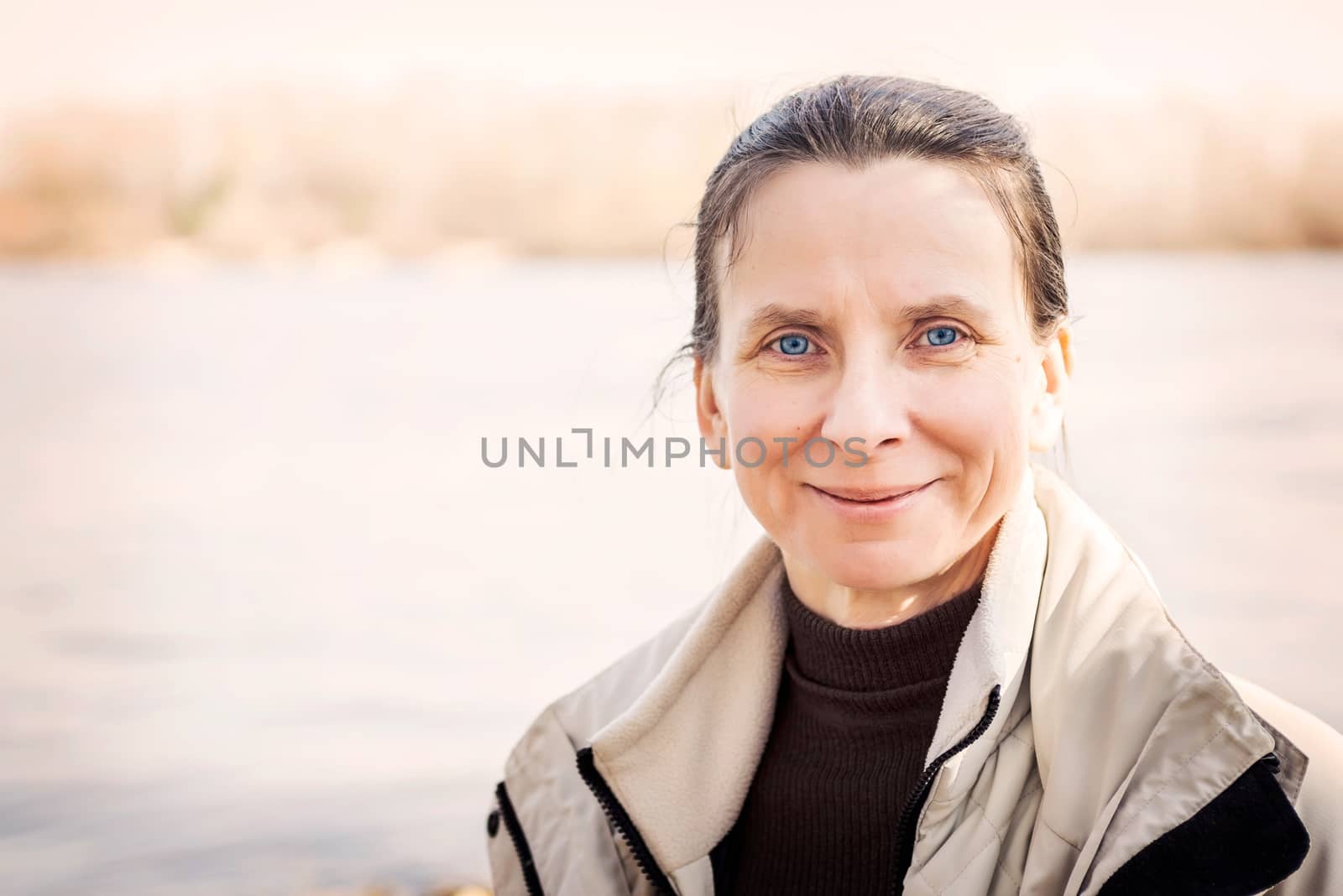 A warm portrait of a nice smiling senior woman close to the river