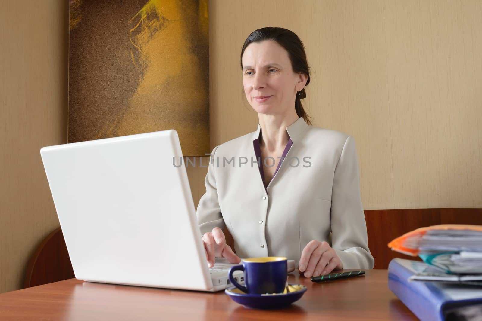 An elegant business woman is using a laptop computer. She is satisfied of her work.