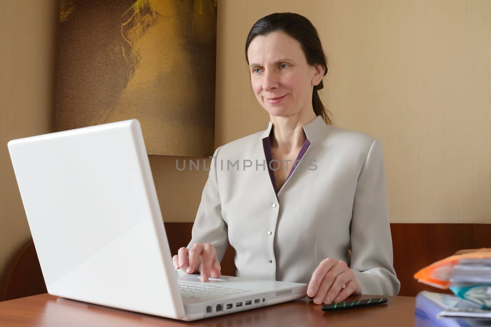 An elegant business woman is using a laptop computer. She is satisfied of her work.