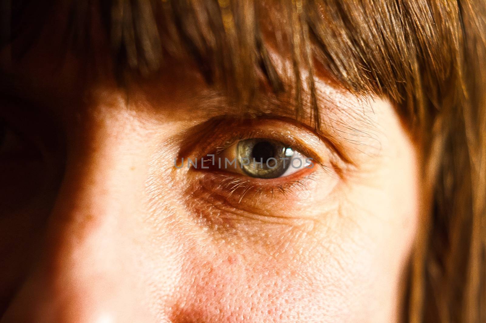 Warm color photo with photographic grain (no noise!)  of a woman's eye with a hard contact lens