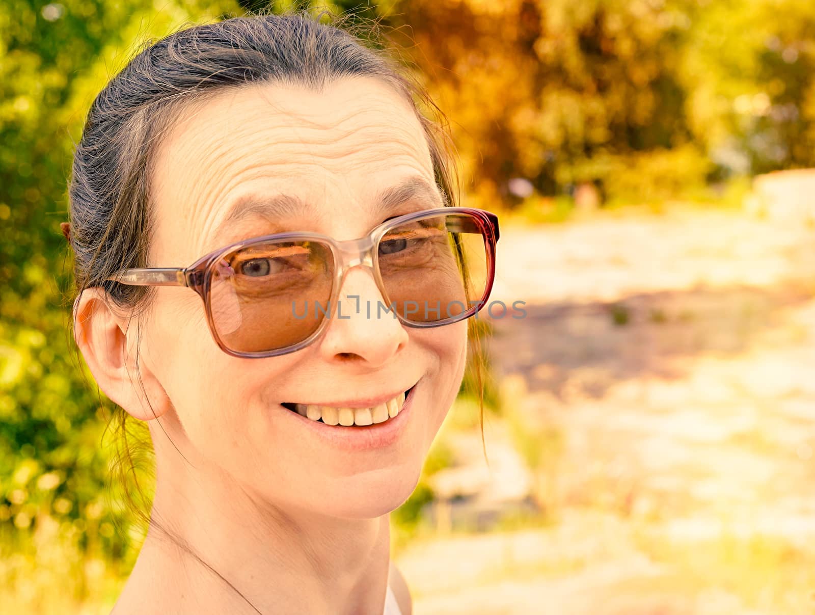 Snapshop of a smiling caucasian adult woman with large vintage sunglasses