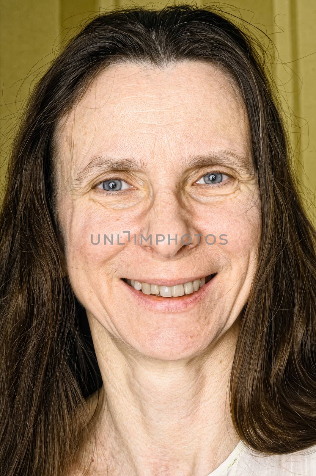 A happy adult woman with long hair is  smiling with a warm and positive expression