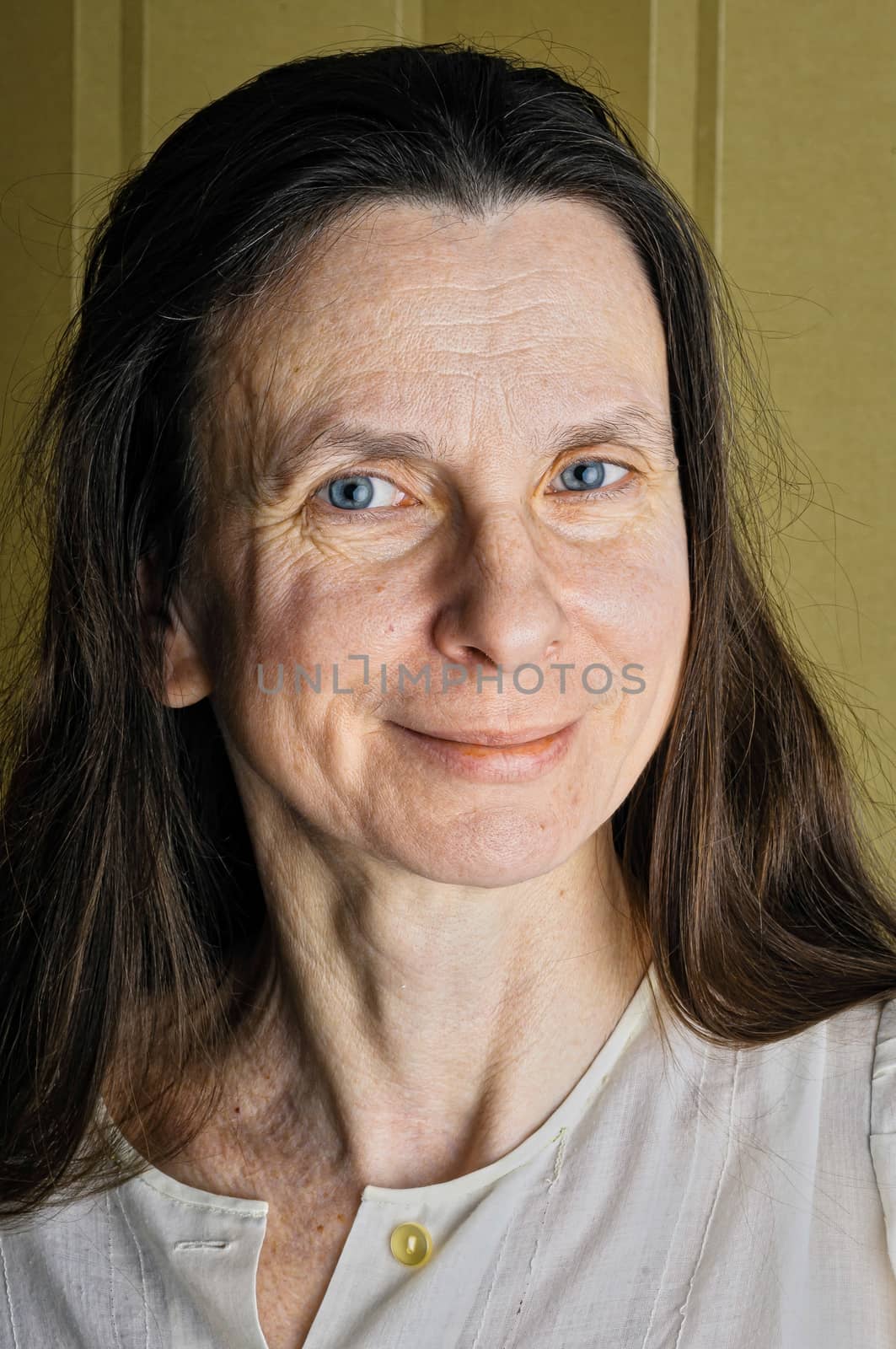 A happy adult woman with long hair is  smiling with a warm and positive expression