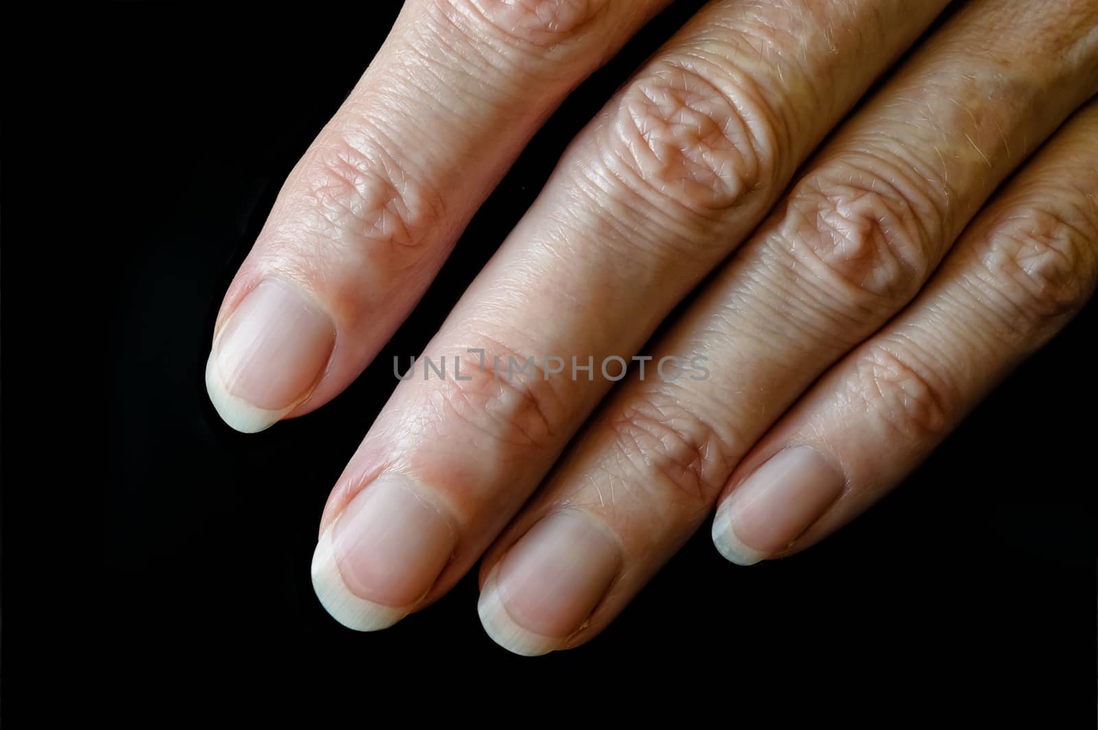 Nice senior woman's fingers on black background