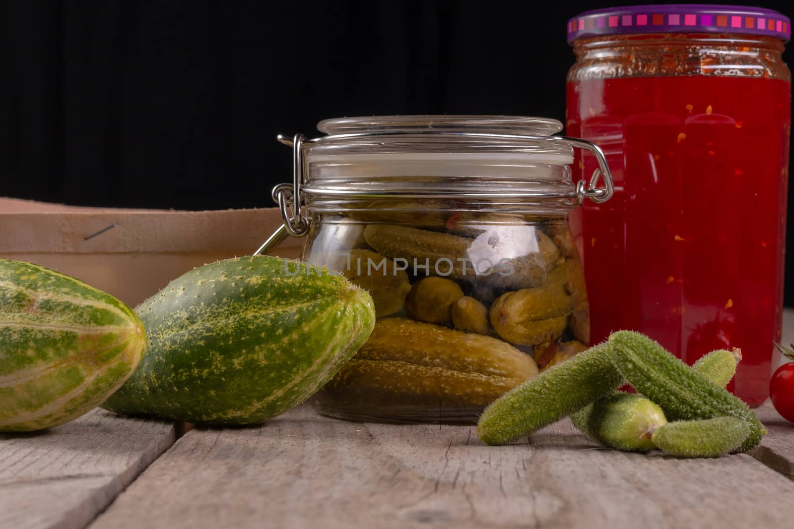 cucumber tomatoes cherry tomato jam canned corinichons on wooden background in studio