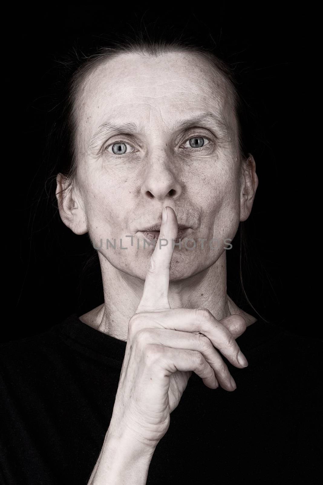 Portrait of an attractive adult woman putting the finger in front of the mouth and saying "Hush!"