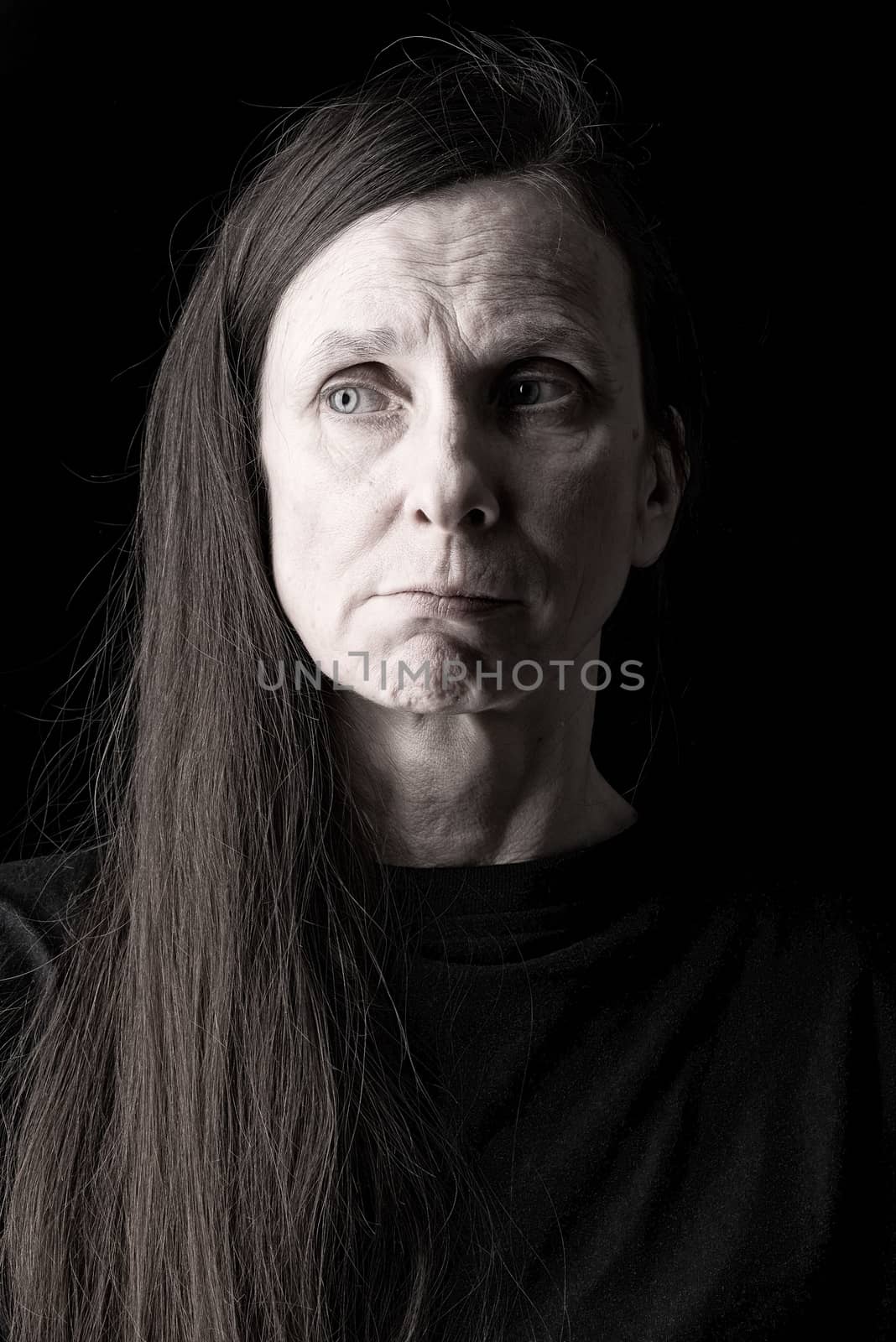 An adult woman with  long hair looks to the right with a doubtful expression on her face
