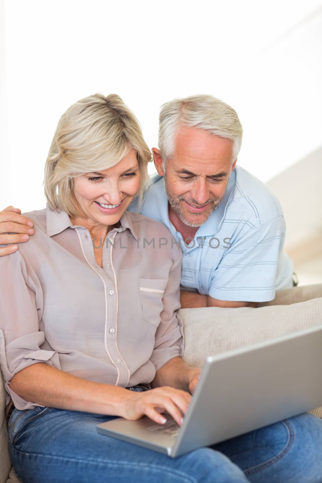Portrait of a happy mature couple using laptop on sofa at home