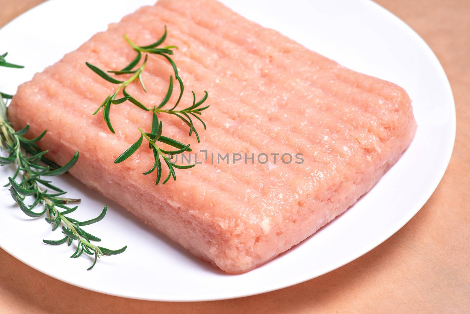 Raw chicken mince on a white plate and on a white background. Delicious diet meat.Close-up of chicken mince. by nkooume