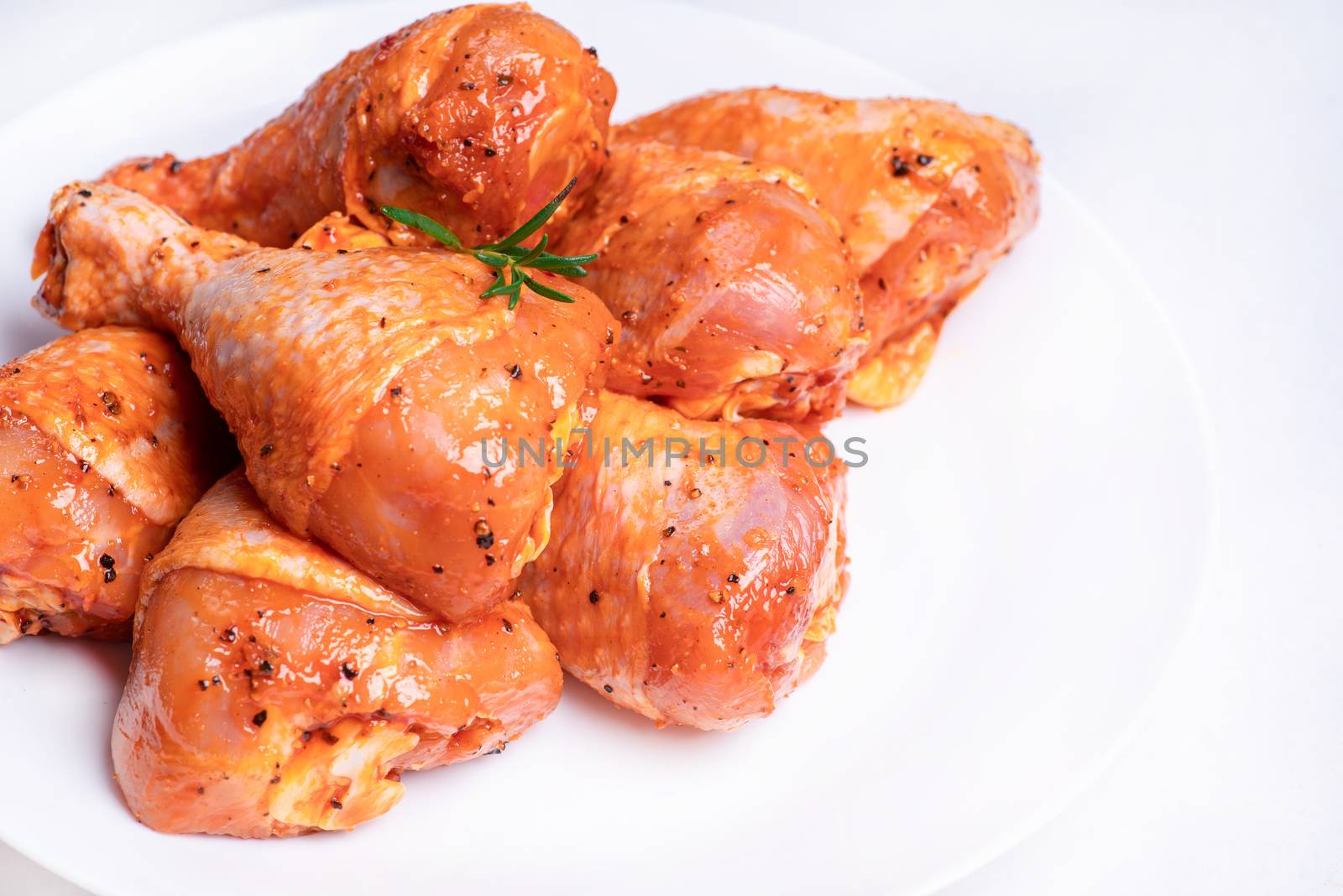 Chicken legs in a red marinade on a white plate. Top view. Chicken meat close-up.Dietary meat. Cooking.Raw marinated chicken legs for grill and bbq.Isolate. by nkooume