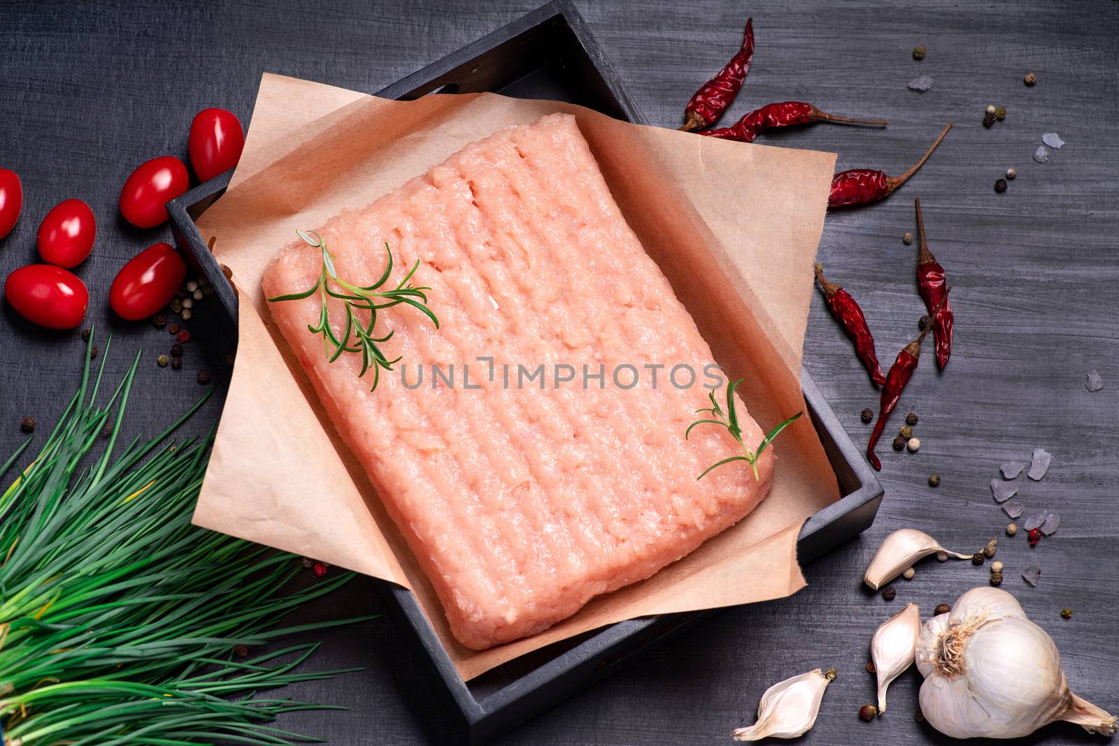 Raw minced chicken on a black plate on a wooden table. Raw Minced meat with herbs and spices,minced chicken close-up. Delicious diet meat. Top view.