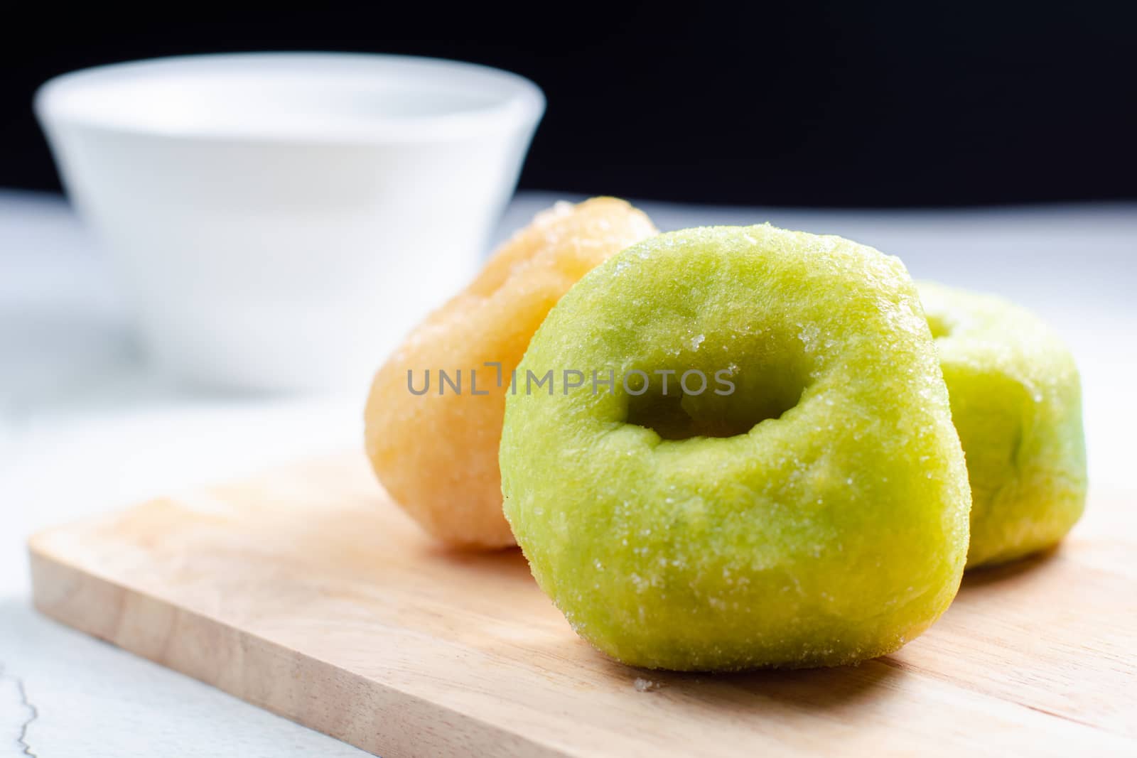 Vanilla and pandan doughnut on wooden chopping board with cup of hot milk. Breakfast concept.