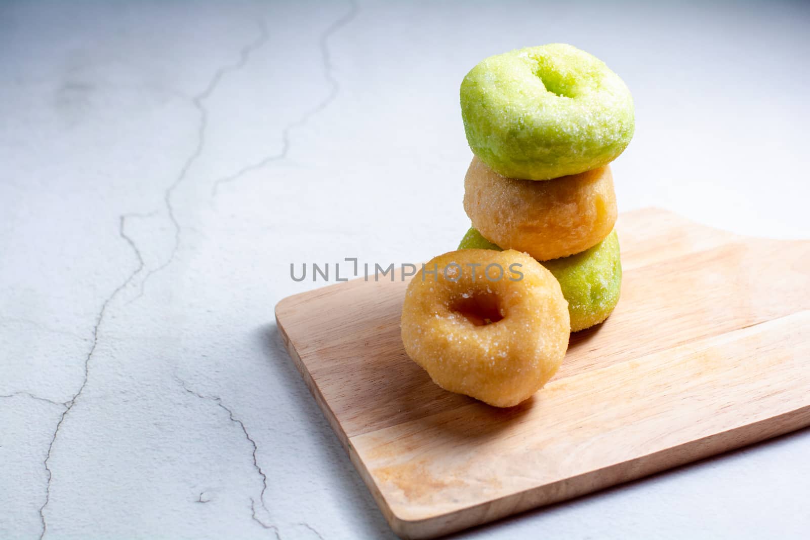 Vanilla and pandan doughnut on wooden chopping board. Breakfast concept.