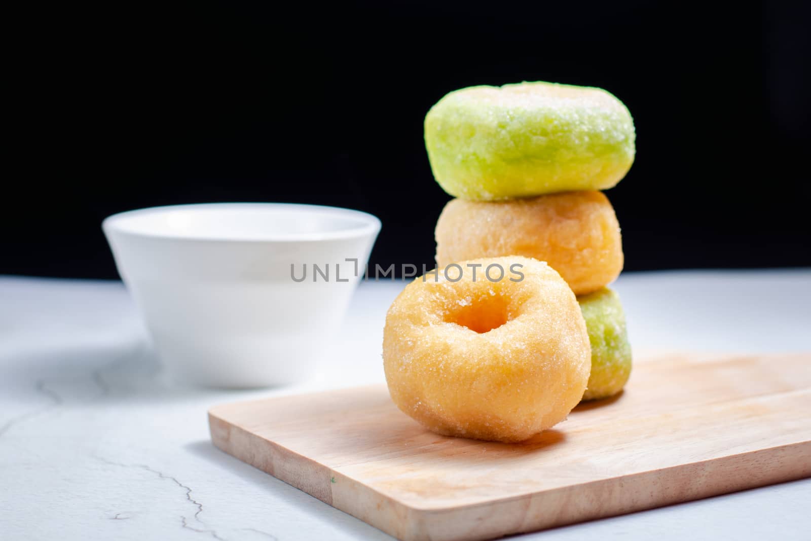 Vanilla and pandan doughnut on wooden chopping board with cup of hot milk. Breakfast concept.