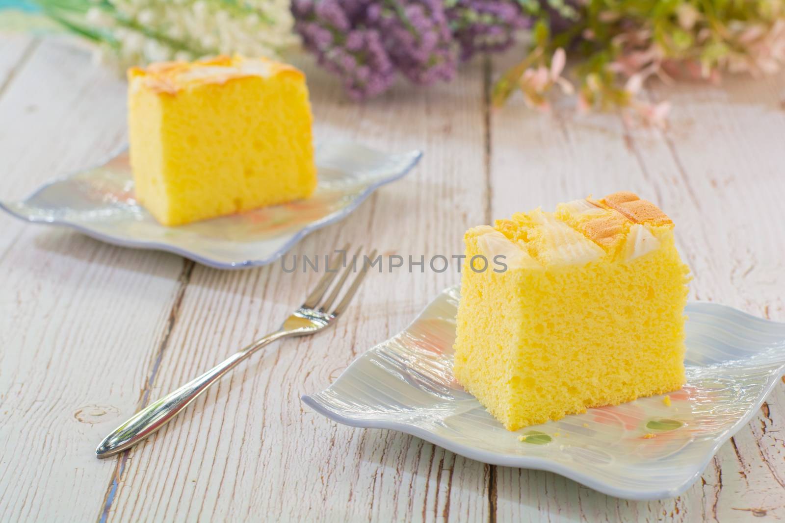 Piece of vanilla chiffon coconut cake on square plate on wooden table. Delicious small bakery for coffee and tea times.