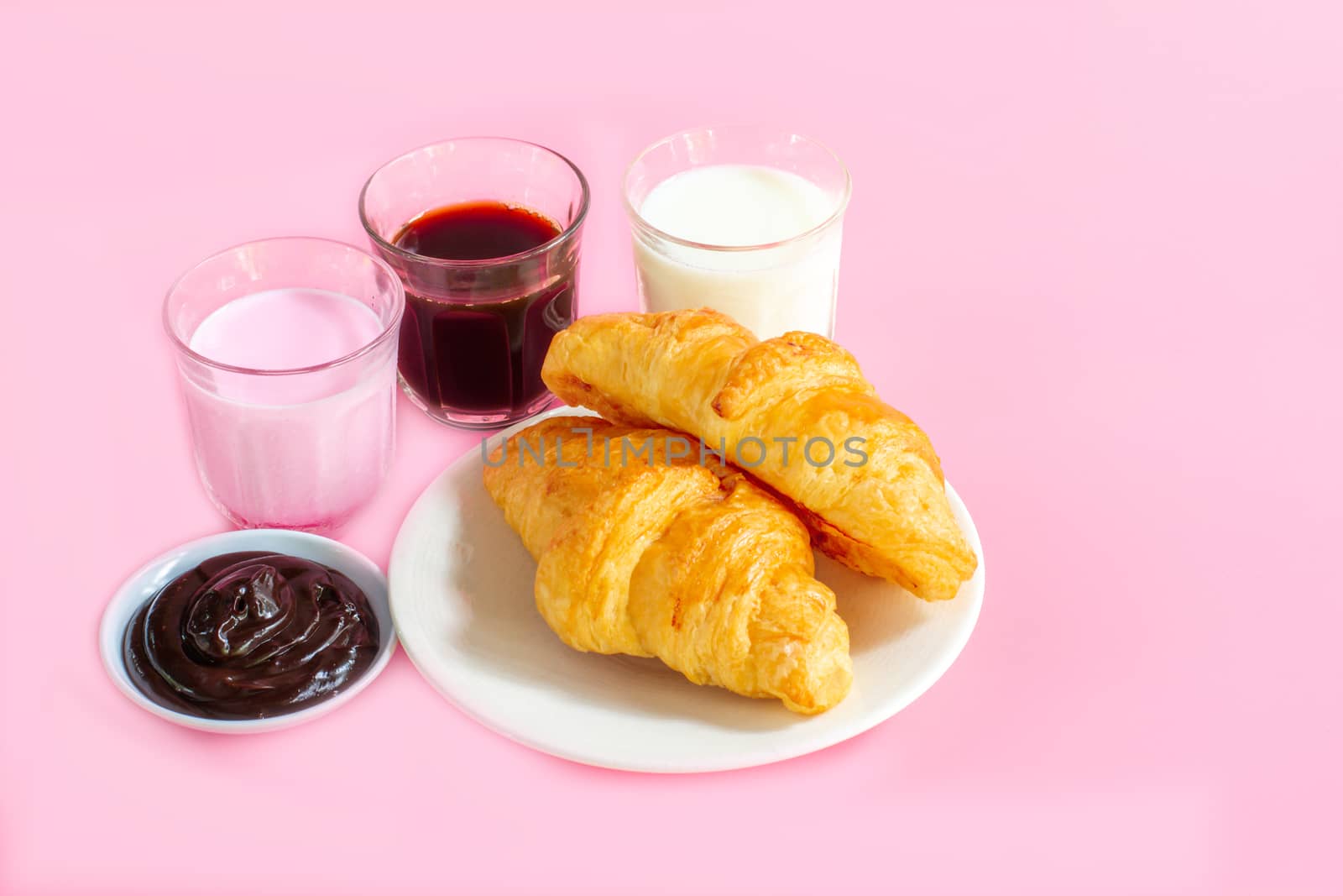 croissants served with glass of Fresh milk, coffee on pink background. Breakfast concept.