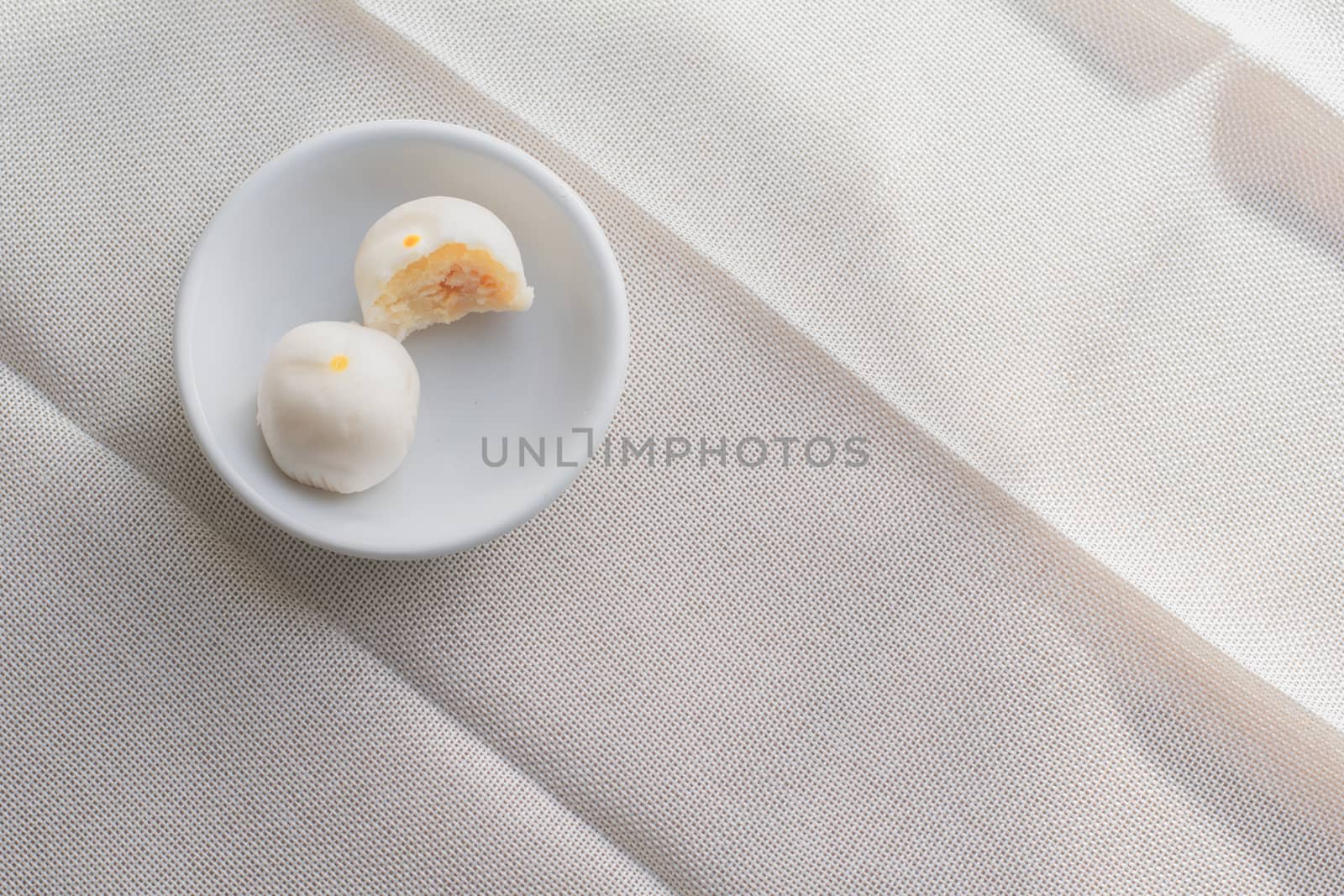 Puff moon cake with sweet mung bean and salt egg yolk in white bowl on table with copy space for your text.