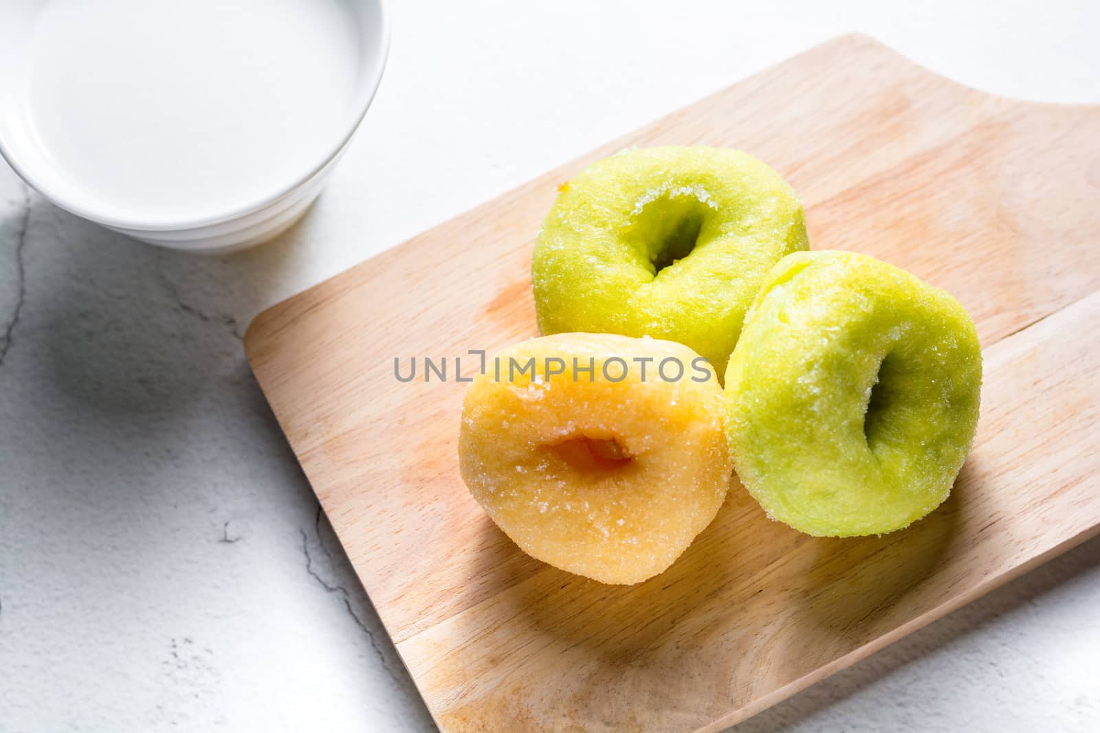 Vanilla and pandan doughnut on wooden chopping board with cup of hot milk. Breakfast concept.