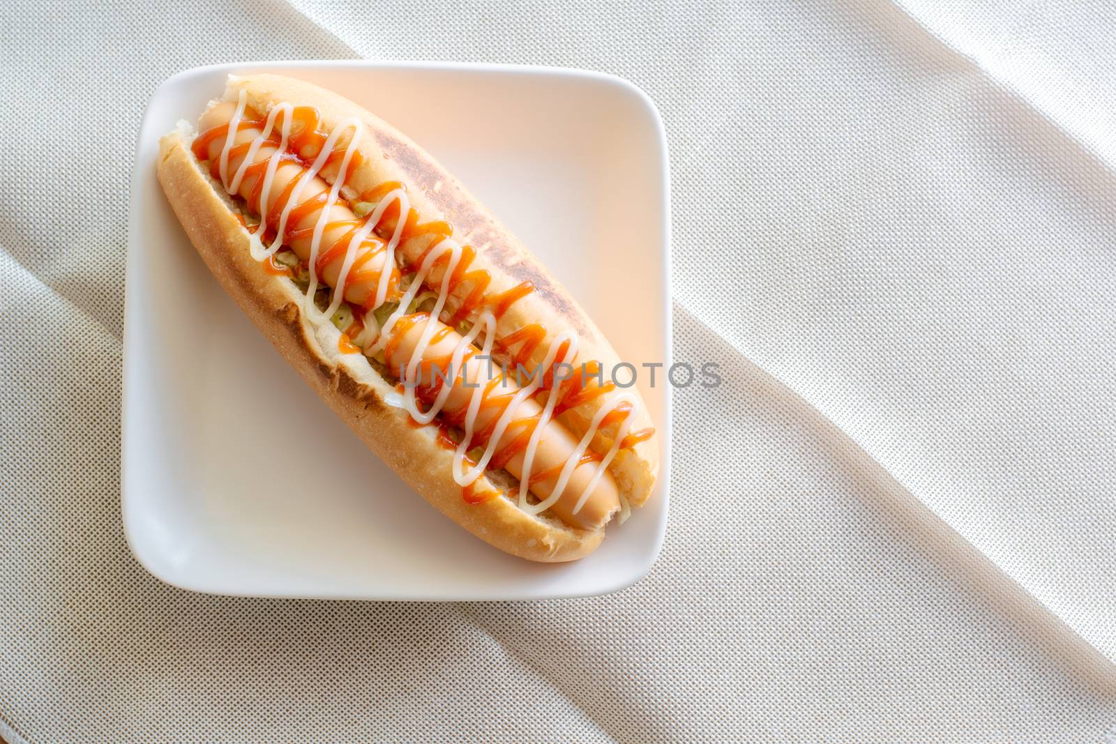 Top view Hot dog with bun and ketchup, mayonnaise on white plate. Sausage sandwich for lunch. Fast food concept.