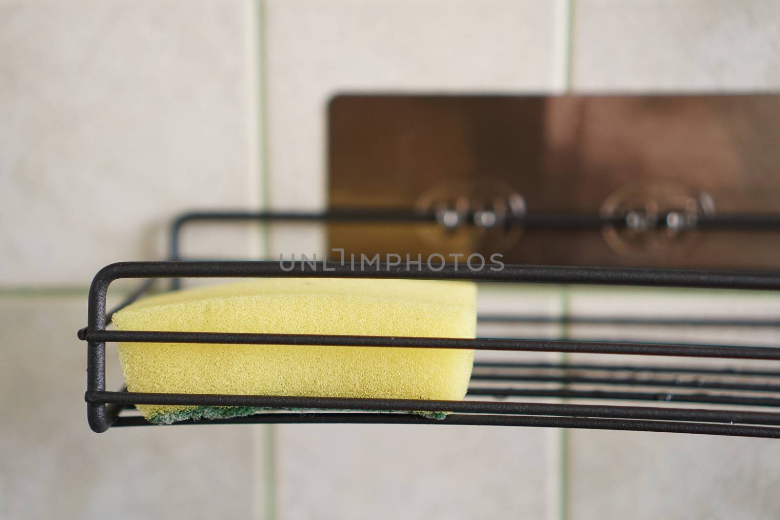 Sponge for washing dishes on metal shelf in kitchen. Concept of cleaning. Close-up interior. No people.