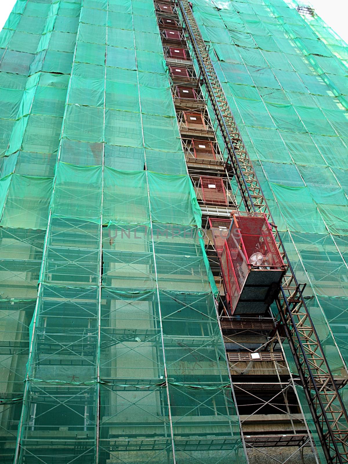 An industrial elevator ascends a modern high rise construction site
