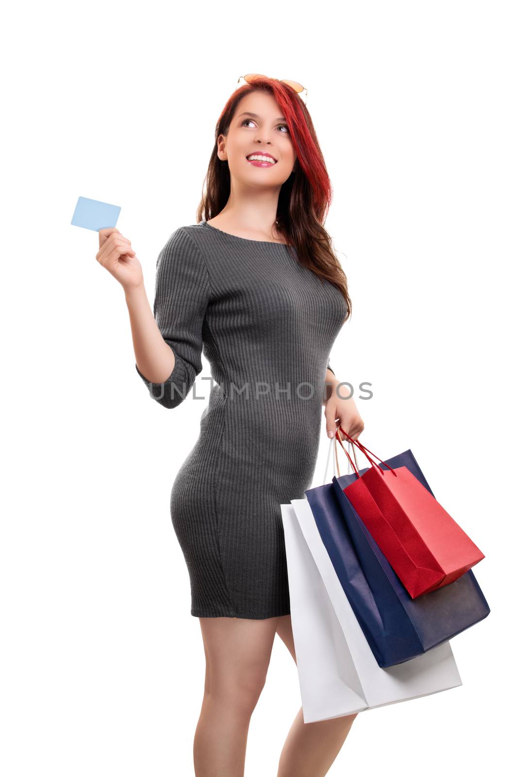 Beautiful young girl in a dress with sunglasses, holing shopping bags and a blank card, isolated on white background. Shopping concept, copy space.
