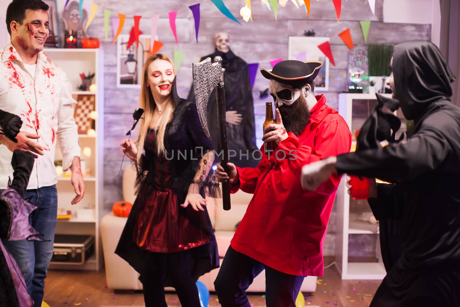 Man dressed up like a pirate holding an axe dancing at halloween celebration with his friends.