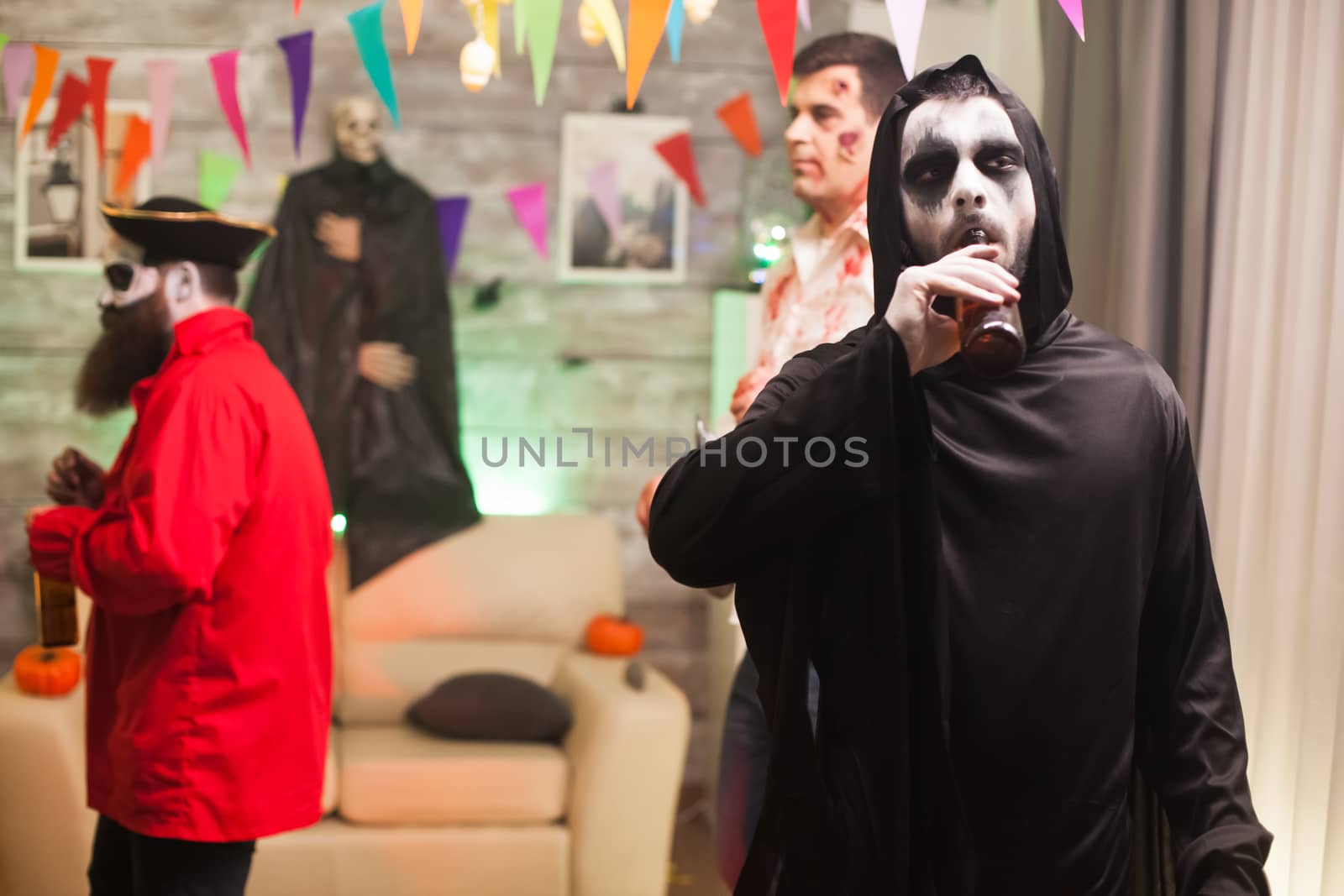 Grim reaper enjoying his beer at halloween celebration. Scary man.