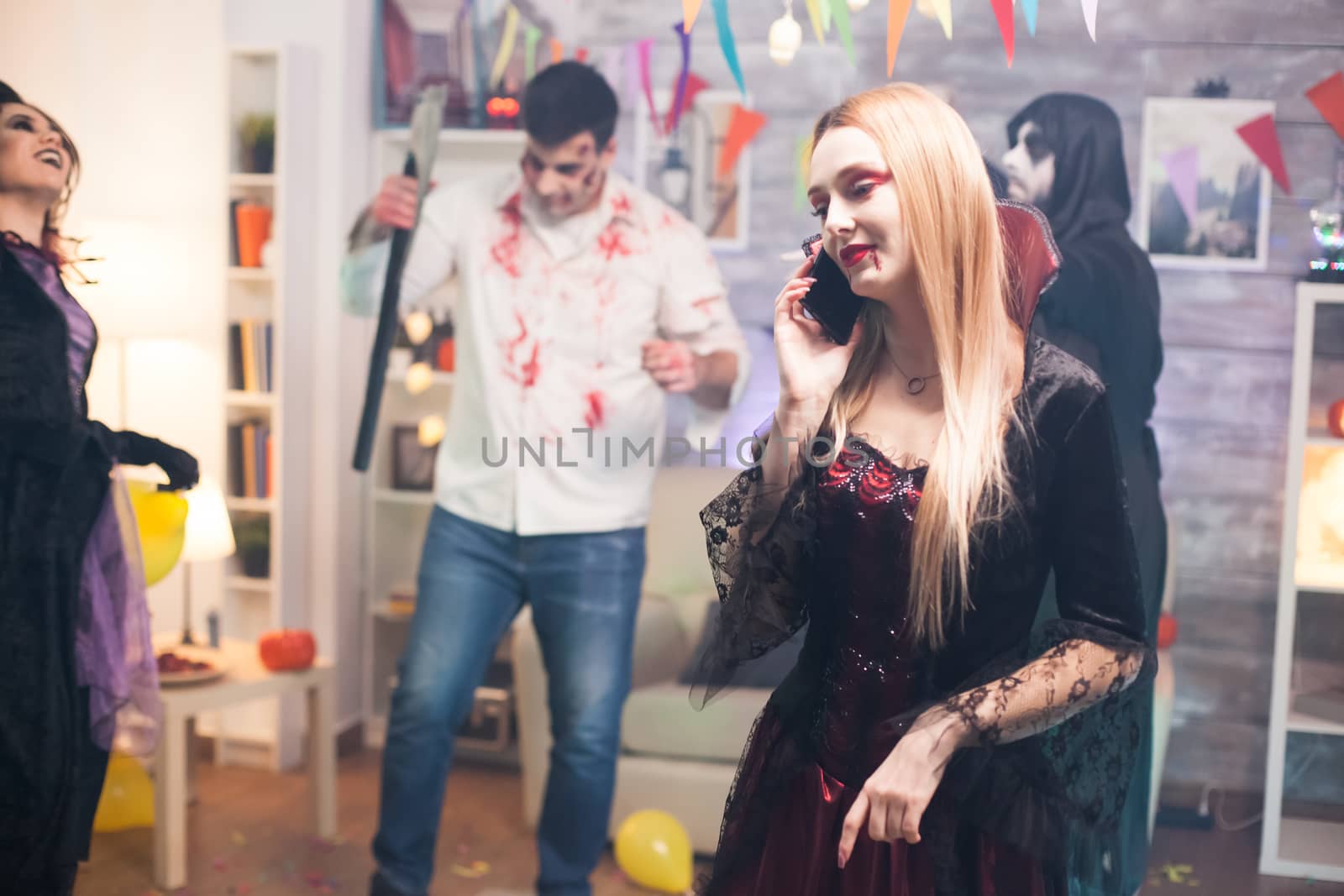 Pretty woman talking on the phone at halloween party by DCStudio