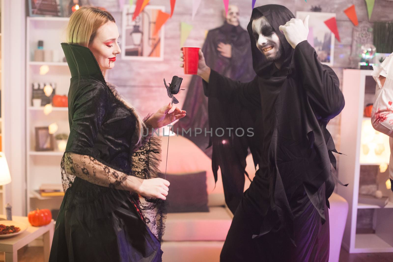 Grim reaper and beautiful vampire woman having fun at halloween party.