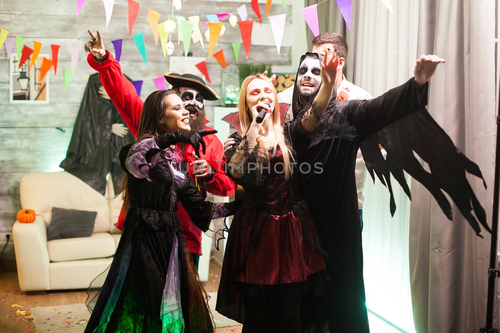 Beautiful vampire woman with bloody lips doing karaoke at a halloween celebration.