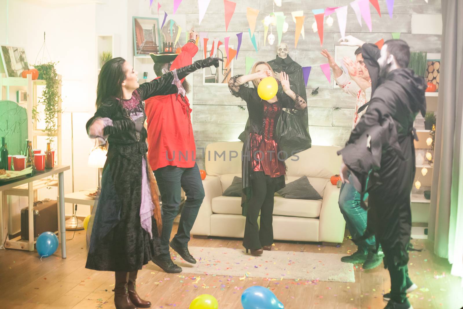 Witch dancing with hands up at halloween party. Spooky costumes.