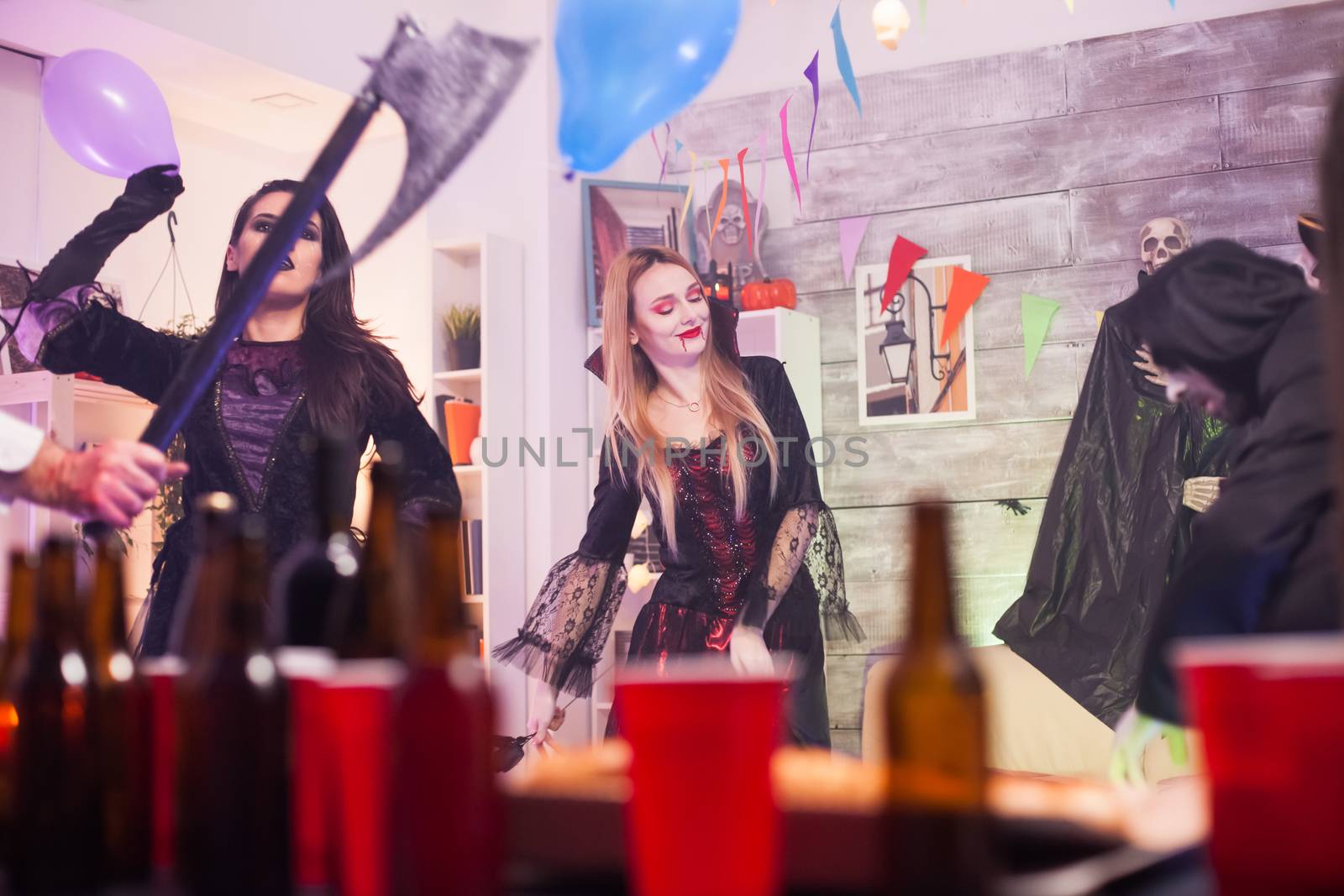 Cheerful vampire woman at a halloween party. Beer caps