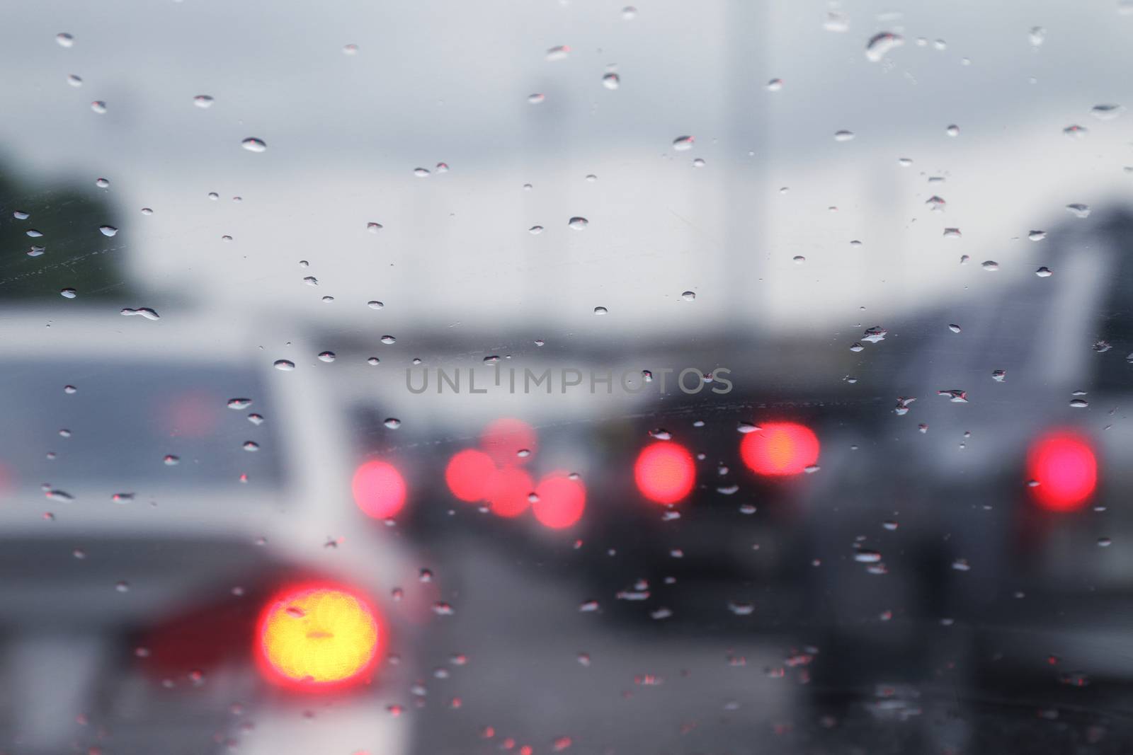 Blurred background traffic car jam and rain drops water on glass with bokeh lighting car by cgdeaw