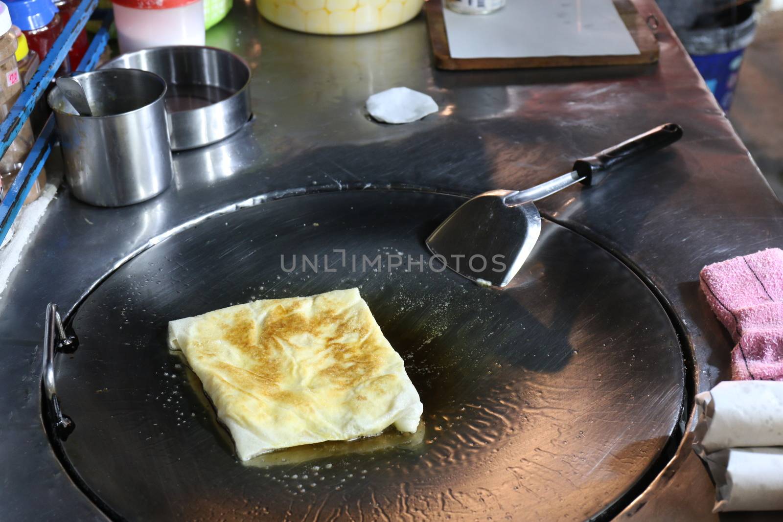 Roti eggs fried (thai word) in a night market street, Indian food, Chapati flatbread, roti canai, dal, curry, teh tarik or pulled tea, acar. Famous indian cuisine