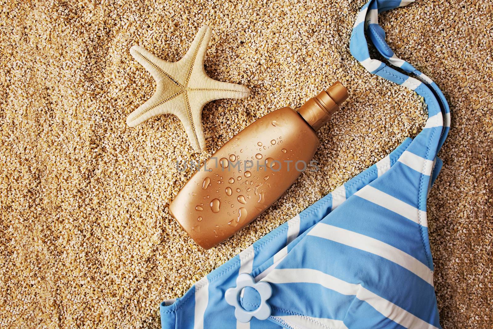 beach wear and accessories. suntan lotion bikini and seashells on sandy beach