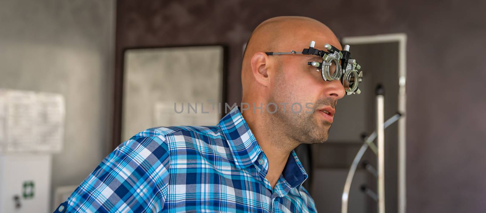 eye examination by optometrist at clinic, young man as patient.