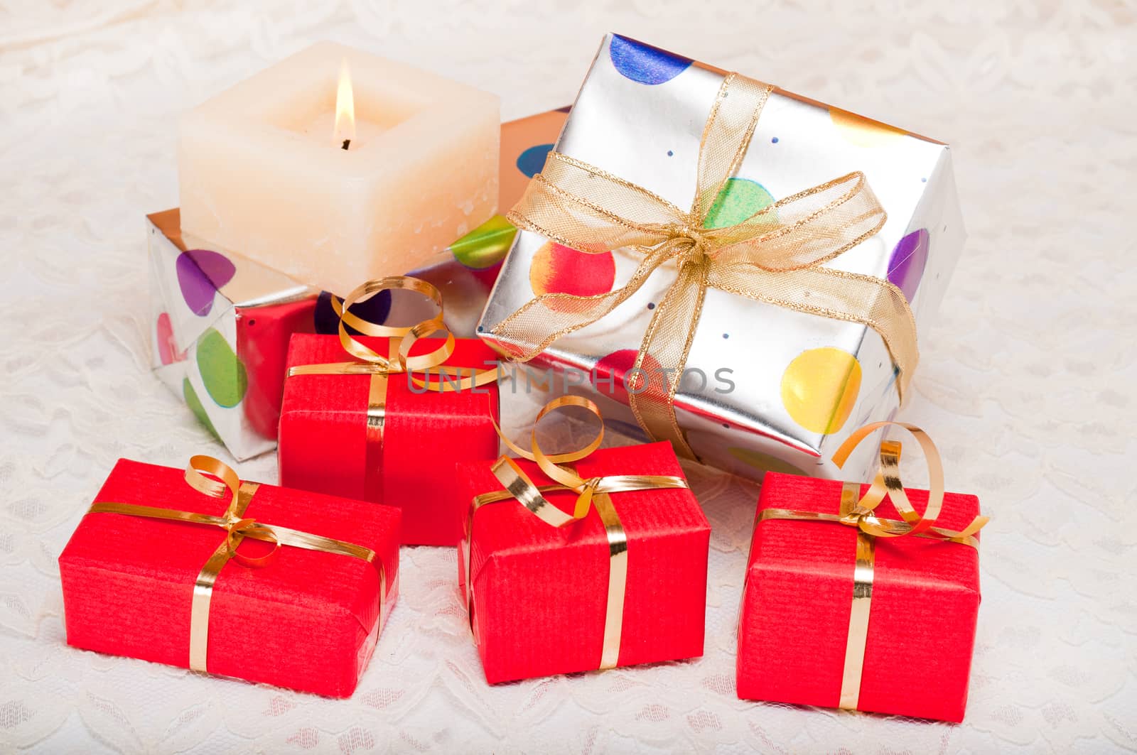Beautiful colorful gift boxes and candle on a background of off-white lace