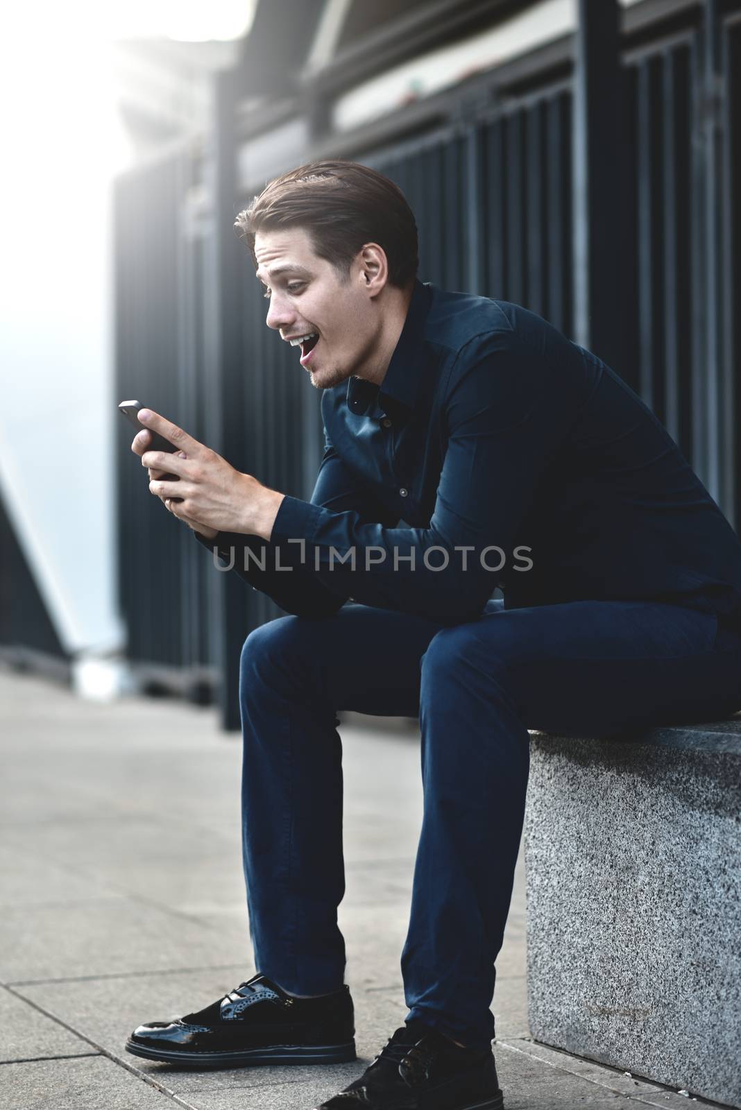 Successful caucasian businessman with smartphone at street in the city.